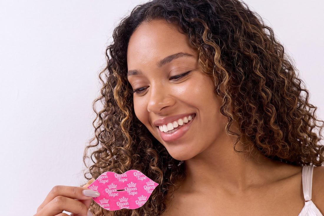 Smiling woman with curly hair holding a hot-pink lip-shaped Queen Hydrating Collagen Mouth Tape, ready for fresher mornings
